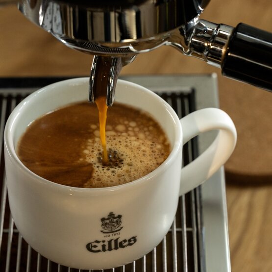 Reichhaltiger Espresso, der in eine Eilles-Tasse fließt und die perfekte Crema auf dem frisch gebrühten Kaffee zur Geltung bringt.