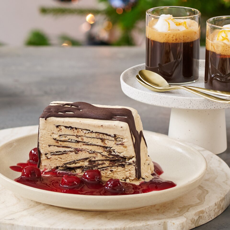 Köstlicher Kaffee Semifreddo mit Kirschsauce und Orangen-Mokka, serviert neben einem festlichen Weihnachtsbaum.