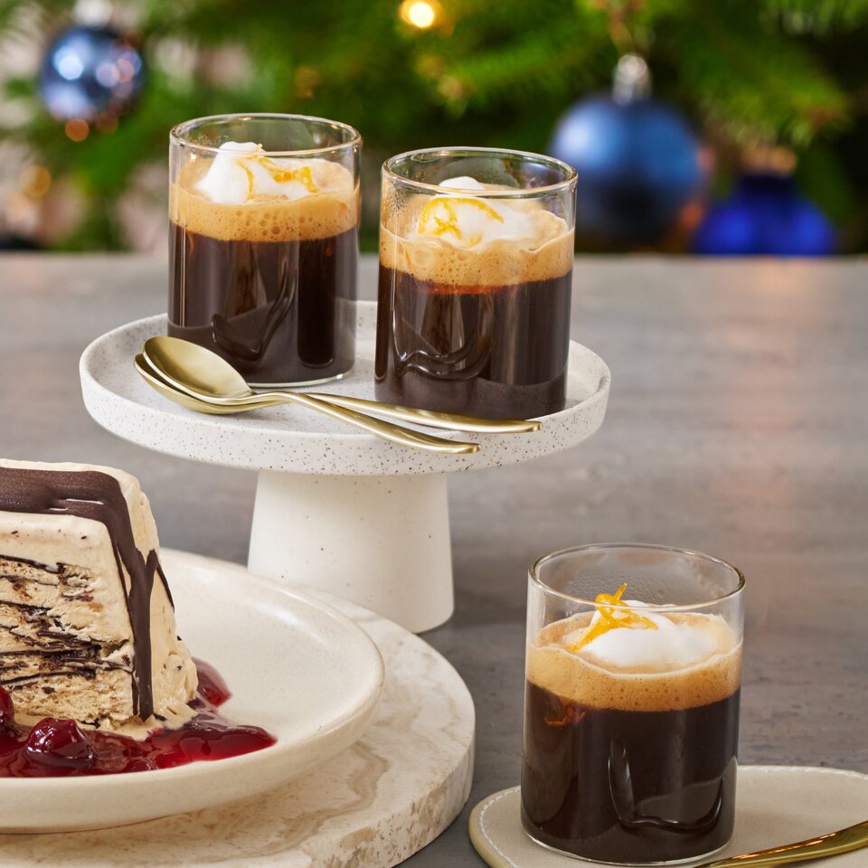 Köstlicher Kaffee Semifreddo mit Kirschsauce und Orangen-Mokka, serviert neben einem festlichen Weihnachtsbaum.