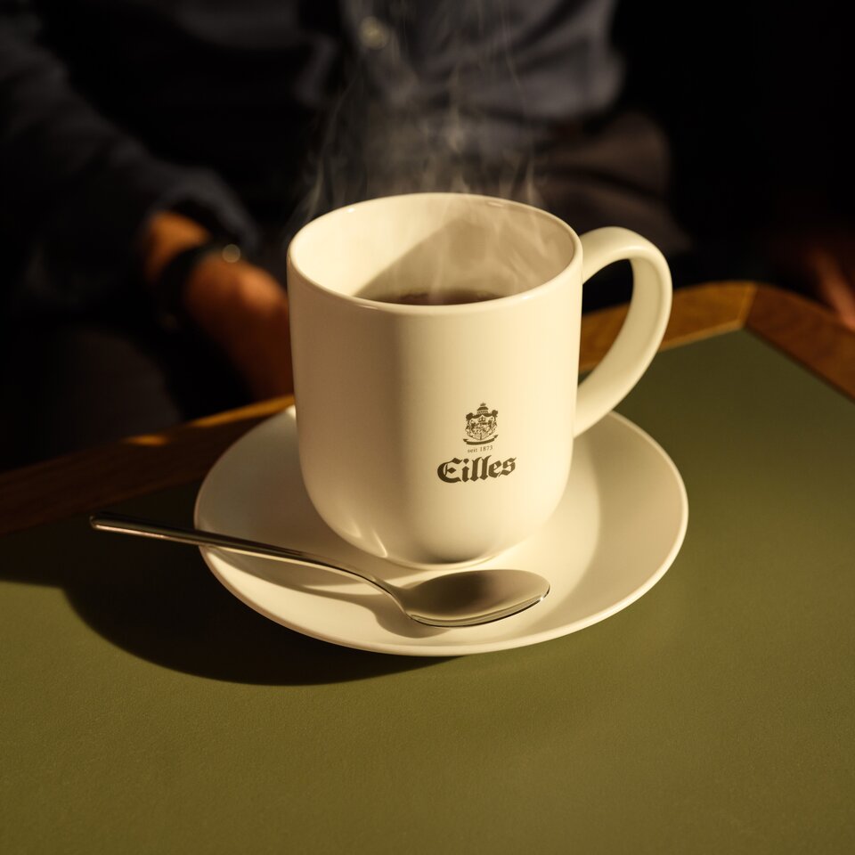Eine dampfende Tasse Eilles-Kaffee auf einer Untertasse, aufgestellt auf einem stilvollen Tisch. Perfekt für Kaffee-Liebhaber.
