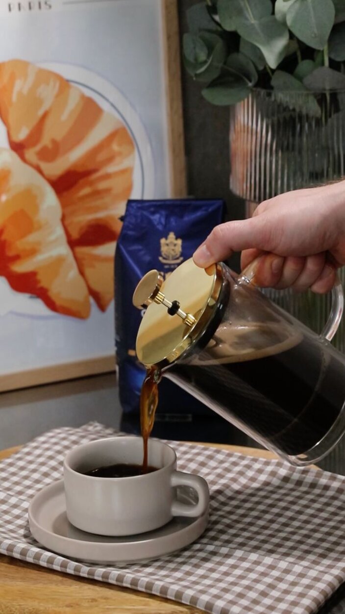 Pouring freshly brewed coffee from a French press into a cup, showcasing a delightful morning ritual.