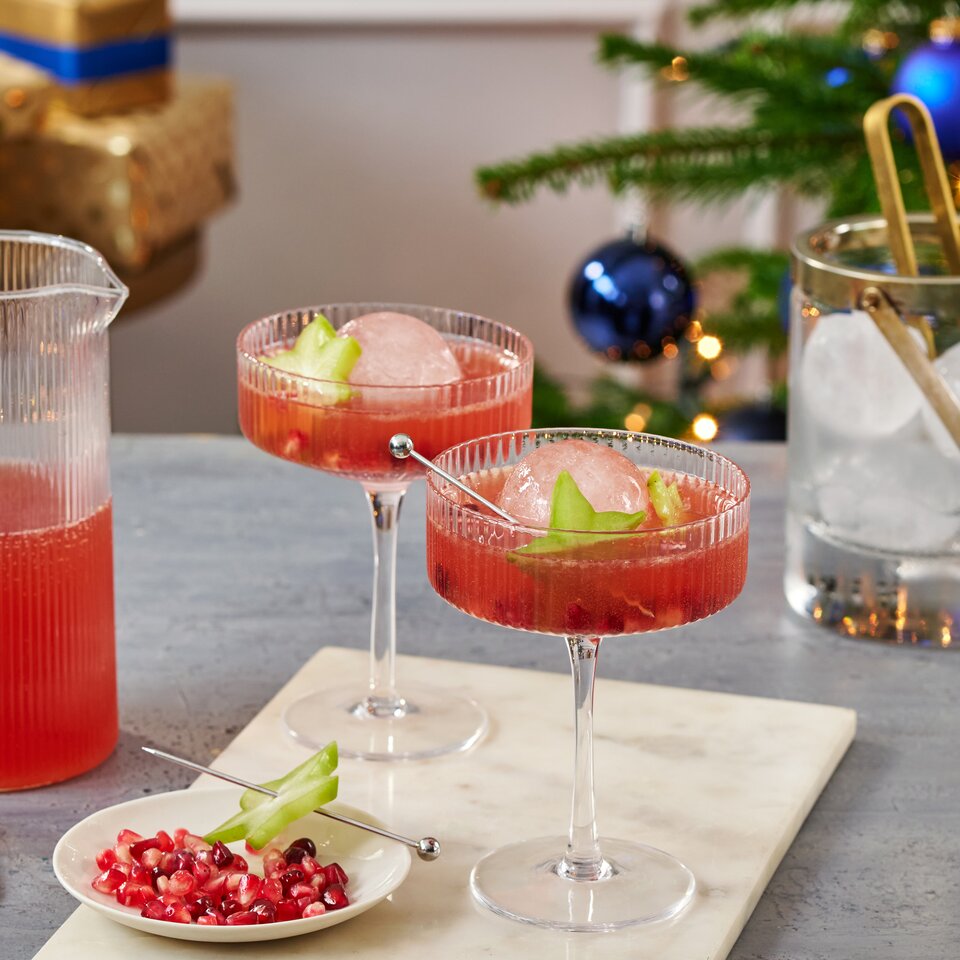 Festliche Cocktails mit Granatapfel und Gurke, perfekt für weihnachtliche Zusammenkünfte, zusammen mit einem stilvollen Getränkekrug.
