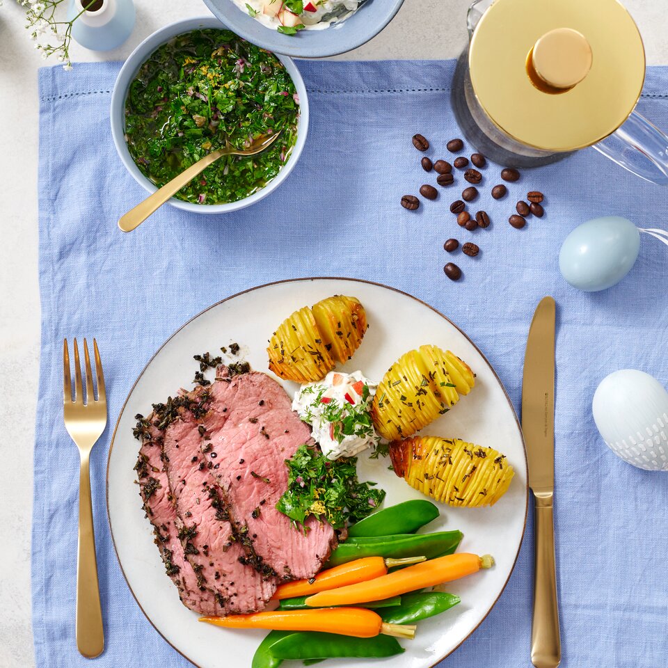 Saftiges Roastbeef mit Kräutern, serviert mit Hasselback-Kartoffeln, kräftigem Gemüse und erfrischenden Dips.