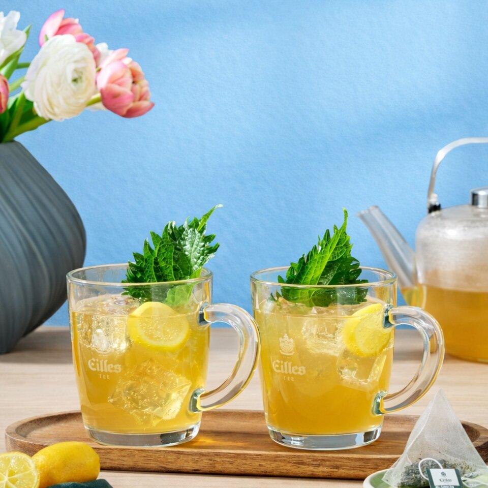 Erfrischender Grüntee Yuzu-Eistee mit Ingwerbier, serviert mit Minze und Zitronenscheiben auf einem Holztablett.