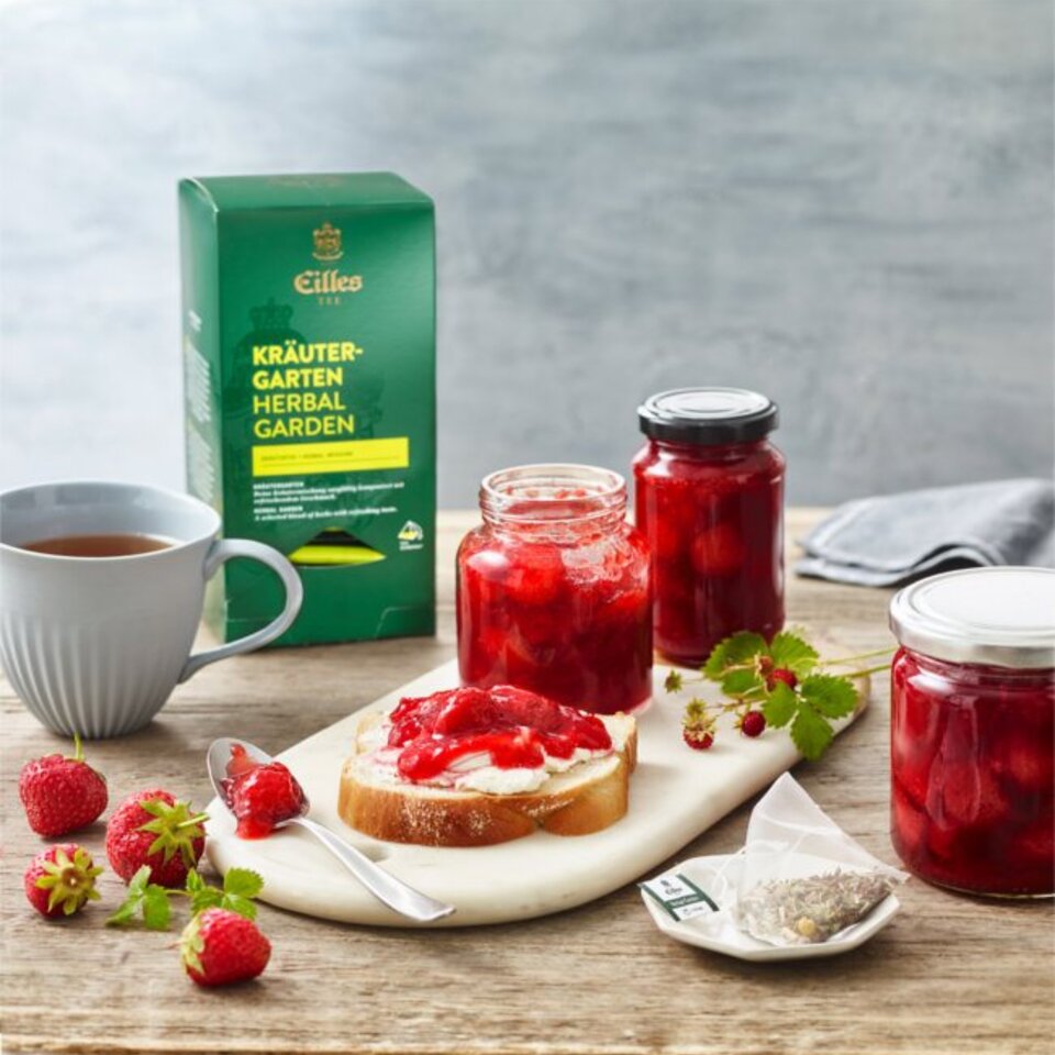 Leckerer Erdbeer-Fruchtaufstrich auf Brot, gepaart mit Kräutertee und frischen Beeren, perfekt für ein köstliches Frühstück.