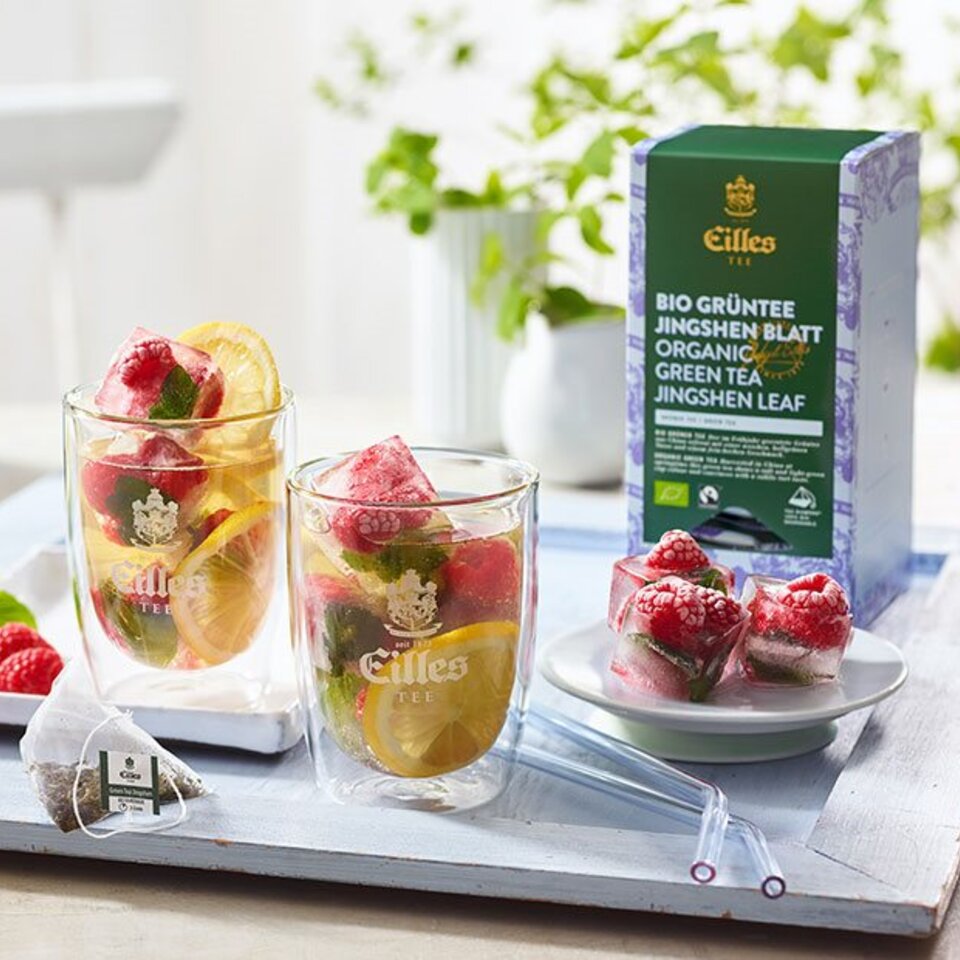 Erfrischender Eilles-Eistee mit Himbeeren und Minze, perfekt für ein Sommergetränk, zusammen mit einer Bio-Grüntee-Verpackung.
