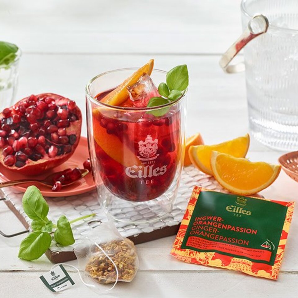 Erfrischender Eilles-Eistee mit Ingwer, Orange und Granatapfel, garniert mit frischem Basilikum und Orangenscheiben.
