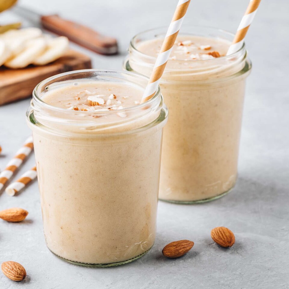 Köstlicher Eistee-Smoothie in Gläsern, mit Mandeln und Kokosflocken, perfekt für eine erfrischende Abwechslung.