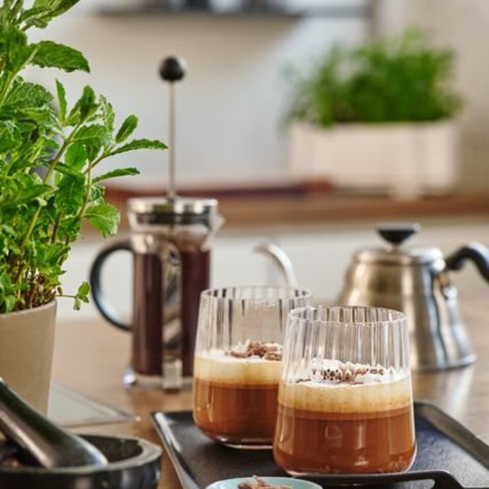 Köstlicher Caffe Crema mit Schokolade in stilvollen Gläsern, in einer hellen Küche, umgeben von frischen Kräutern.