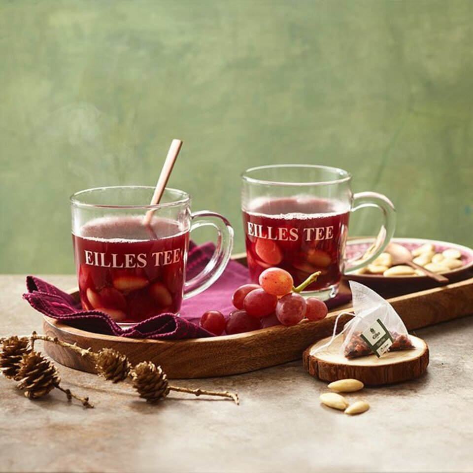 Dampfender Fruchtpunsch in Eilles-Tee-Gläsern, serviert mit Weintrauben und Nüssen auf einem Holztablett, perfekt für gemütliche Abende.