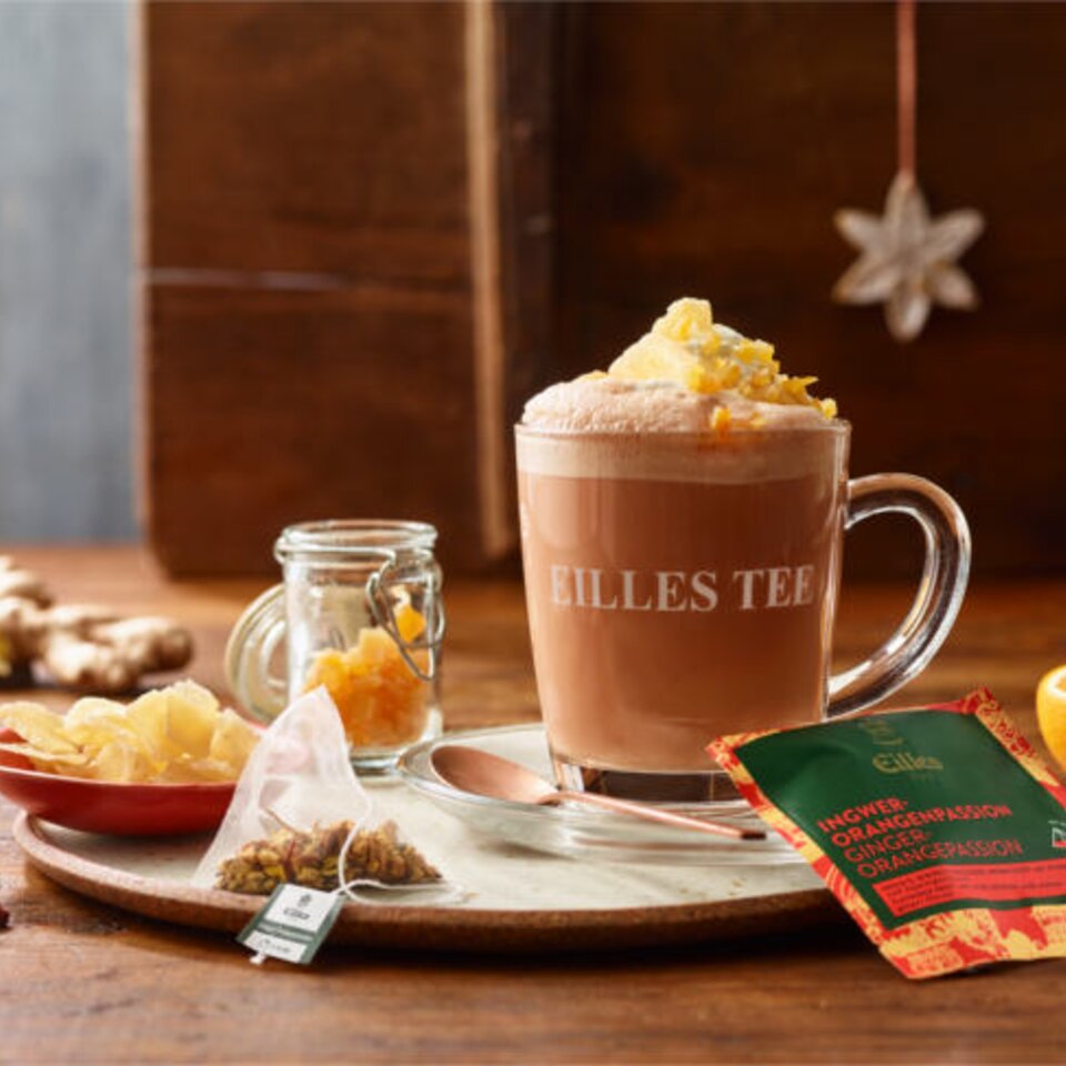 Köstlicher Eilles Tee Ginger Orange Passion Punch im Glas, garniert mit Schlagsahne und Trockenfrüchten.