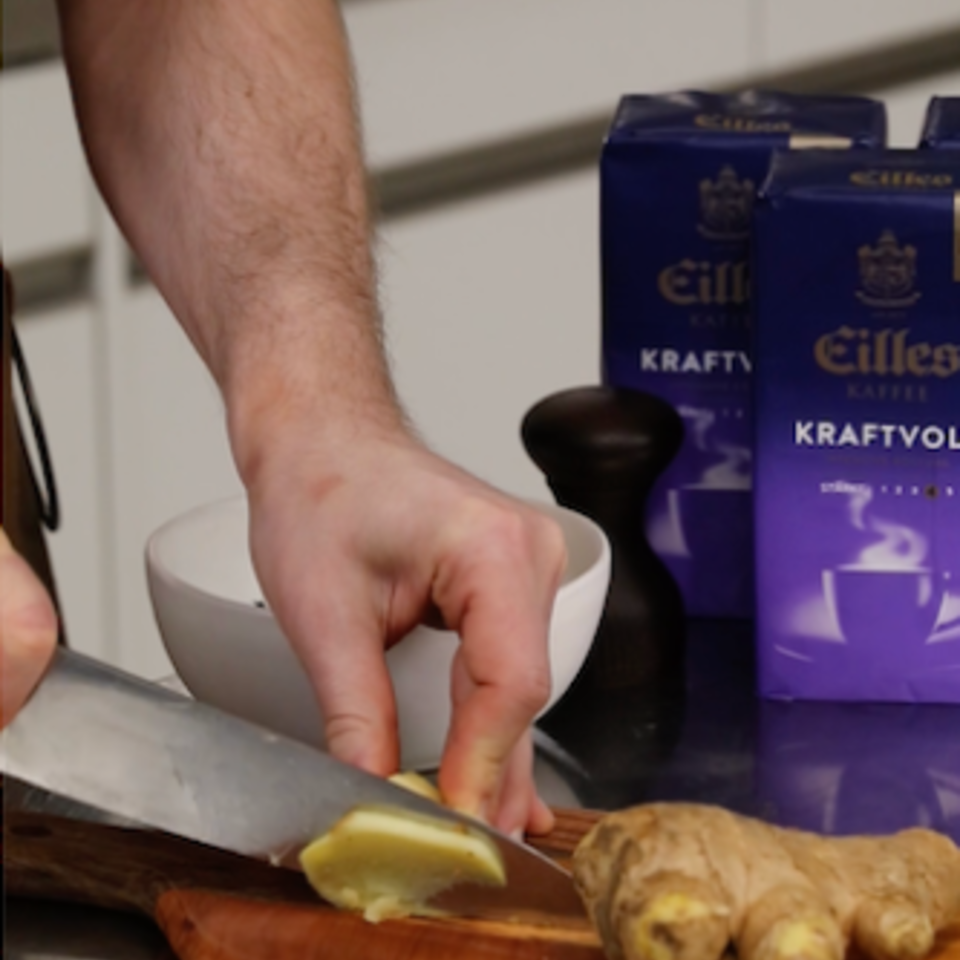 Zubereitung von Ingwer für ein erfrischendes Ingwer-Kaffee-Rezept, mit der Verpackung von Eilles Kaffee im Hintergrund.