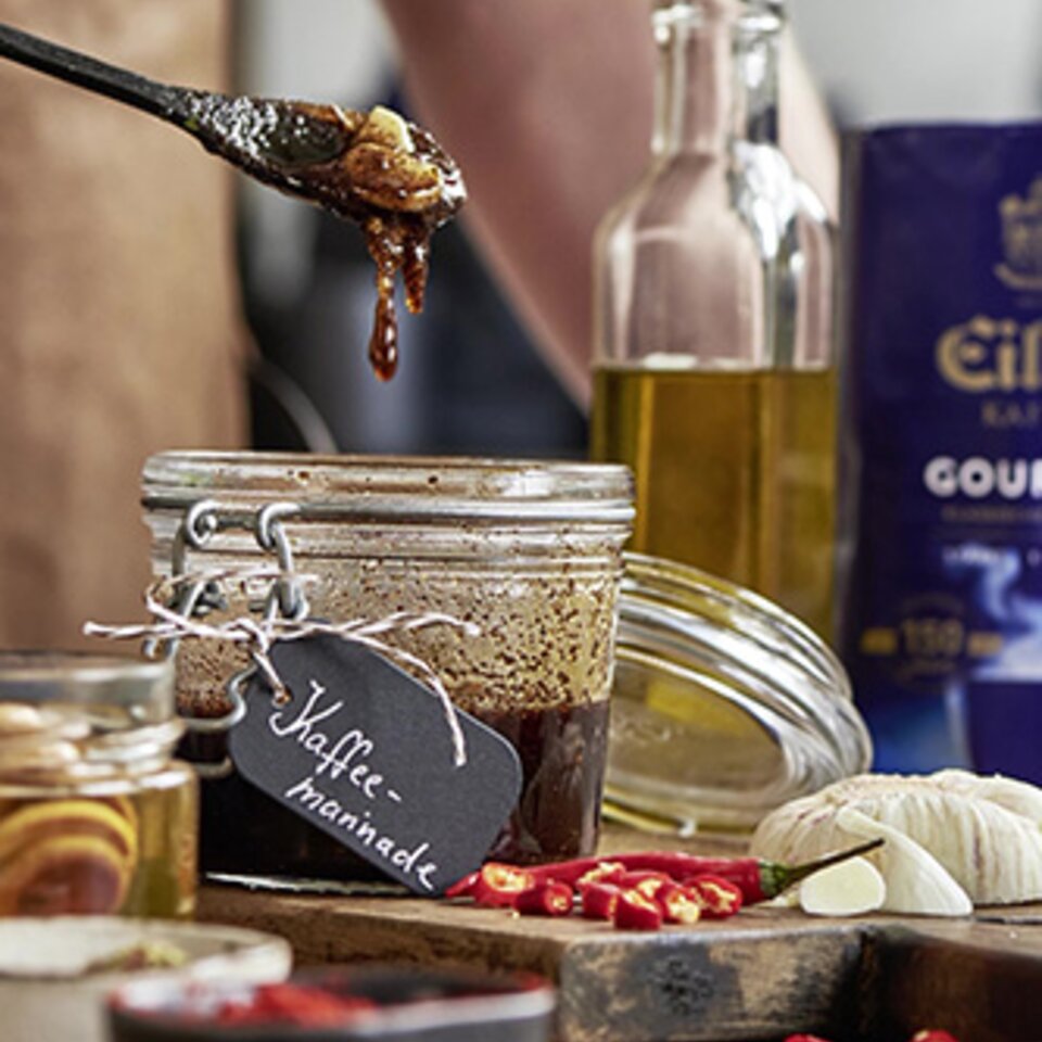 Reichhaltige Kaffeemarinade im Glas, umgeben von Gewürzen, bereit, Ihre Gerichte mit einzigartigen Aromen zu verfeinern.