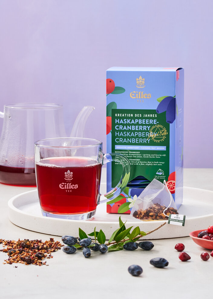 Čaj Eilles Tea Haskapberry-Cranberry v pohári s bobuľami a obalom, ideálny pre milovníkov čaju.