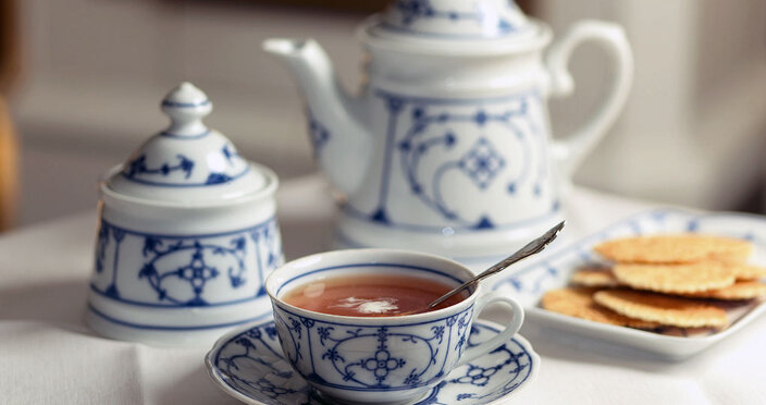 Vychutnejte si šálek ostfriesského černého čaje s tradičními sušenkami podávanými v elegantním porcelánu.
